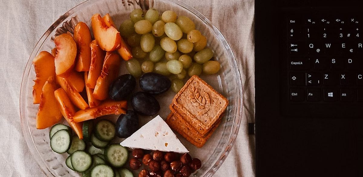 A delightful snack plate with fruits, cheese, and a laptop for a healthy lifestyle.