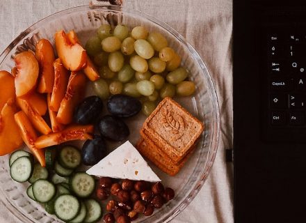 A delightful snack plate with fruits, cheese, and a laptop for a healthy lifestyle.